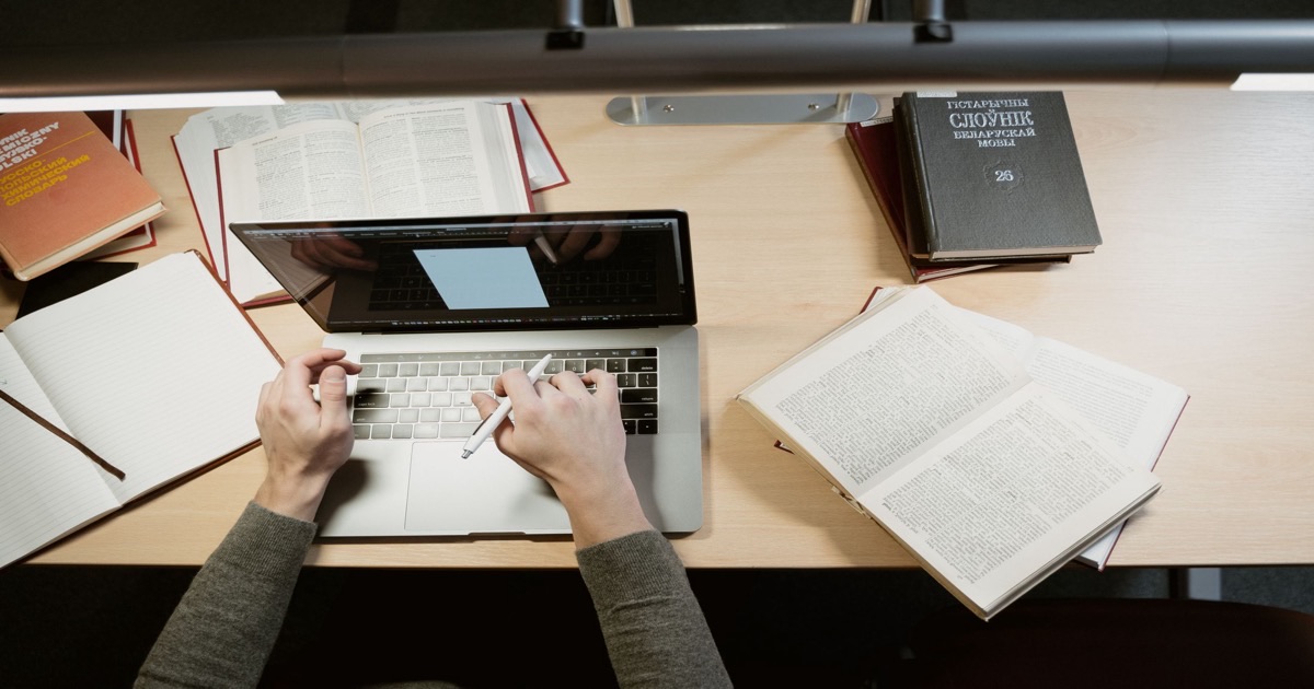 Student organising research notes beside a laptop